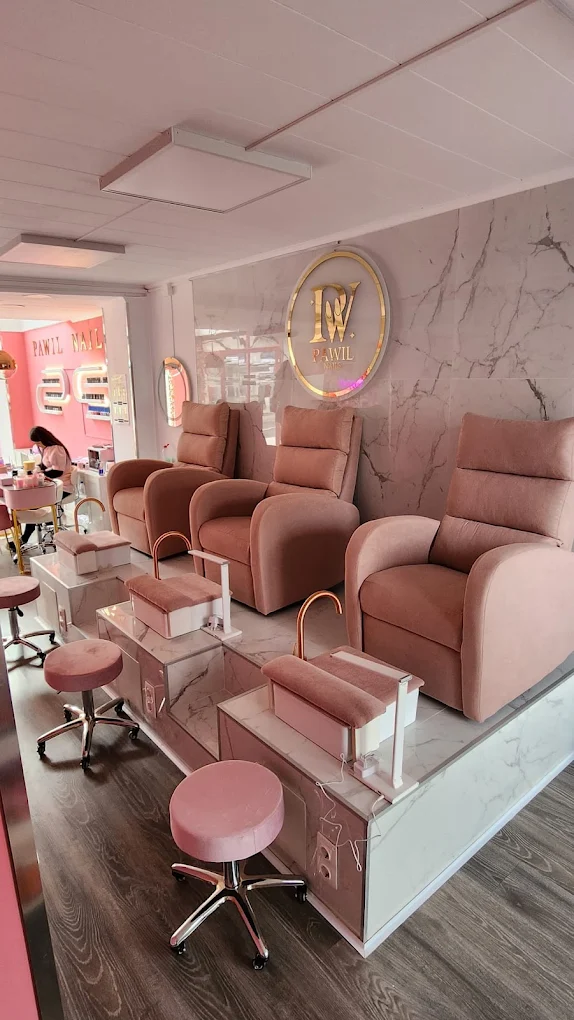 Zona de pedicura de Pawil Nails con sillones de terciopelo y panel de mármol con logo dorado