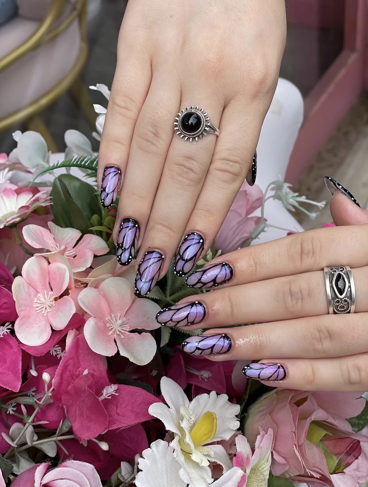 Nail art de mariposas en tonos lilas y negros sobre flores rosas